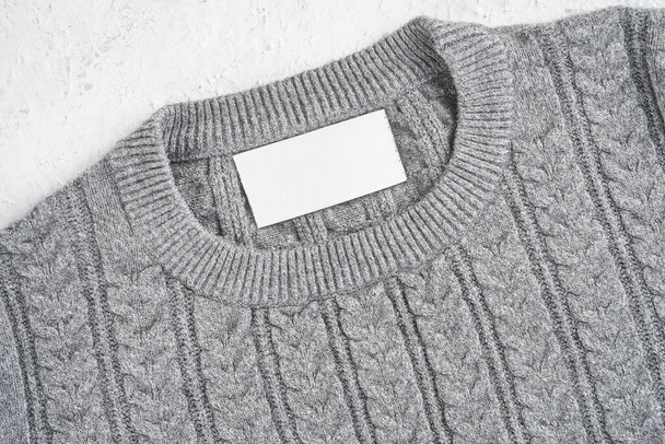 Burla de una etiqueta interior en el cuello de un bonito suéter de lana gris. Espacio en blanco para colocar un logotipo, texto o imagen - Foto, imagen