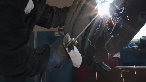 A welder welds an iron disc. Close-up of the electrode with sparks and flashes. Industrial background.  - Footage, Video