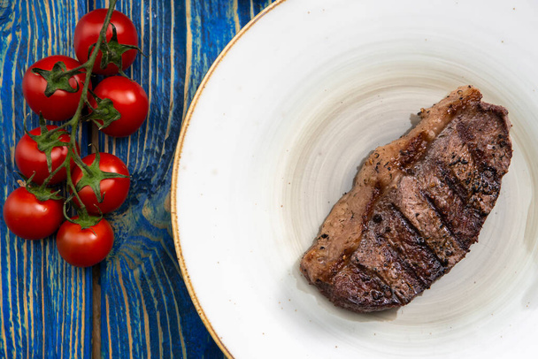 Grilled steak ,cherry tomatoes salt and pepper on wooden table. - Zdjęcie, obraz