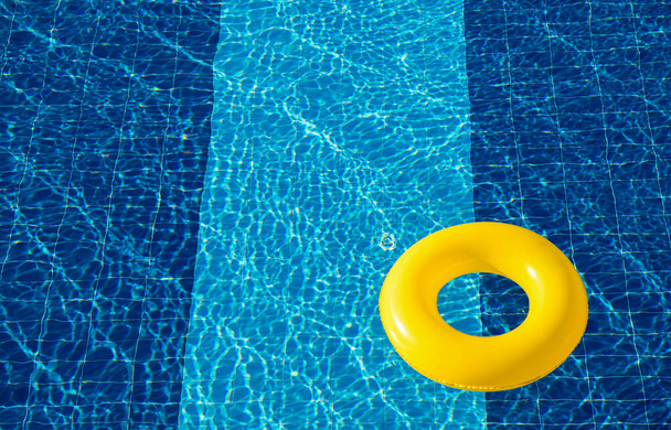Galleggiante piscina gialla, anello galleggiante in una rinfrescante piscina blu - Foto, immagini