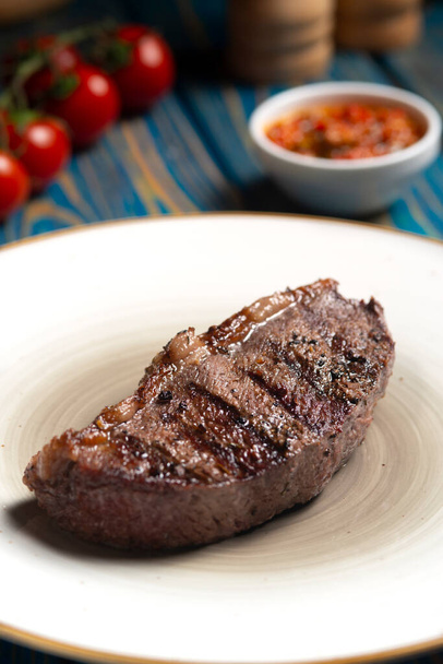 Roasted steak ,cherry tomatoes, salt and pepper on blue  wooden table. - Foto, afbeelding