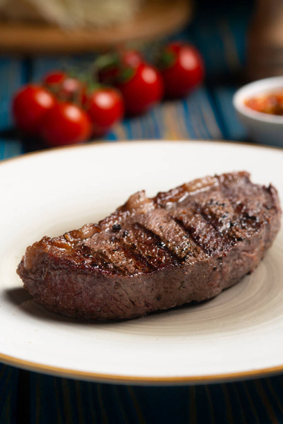Roasted steak ,cherry tomatoes, salt and pepper on blue  wooden table. - Foto, immagini