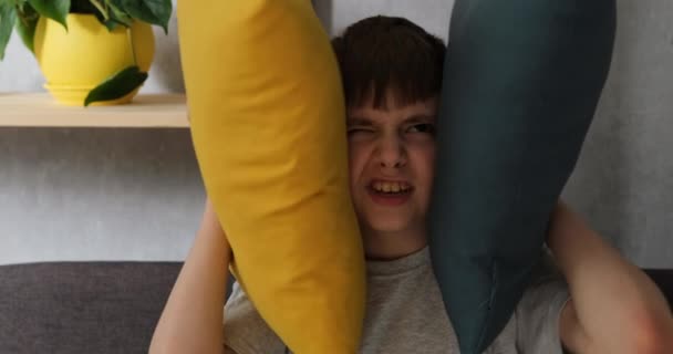 Cansado de raiva menino cobre travesseiros seus gritos ouvidos e pede para parar de fazer barulho. Retrato closeup luz do dia - Filmagem, Vídeo