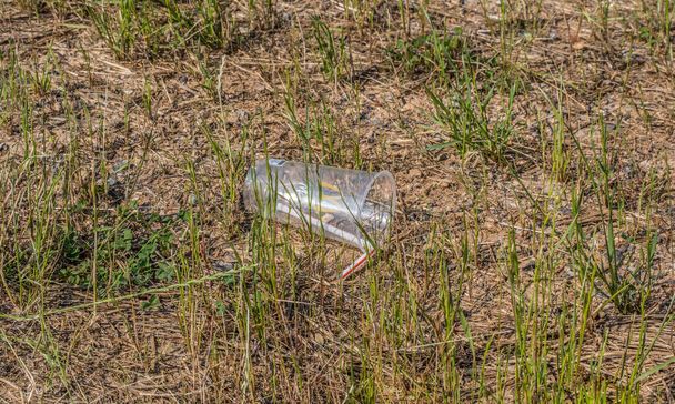Cumming, Georgia USA - May 24, 2021  A plastic McDonald's beverage cup with a straw dumped on the ground alongside the road polluting the environment - Photo, Image