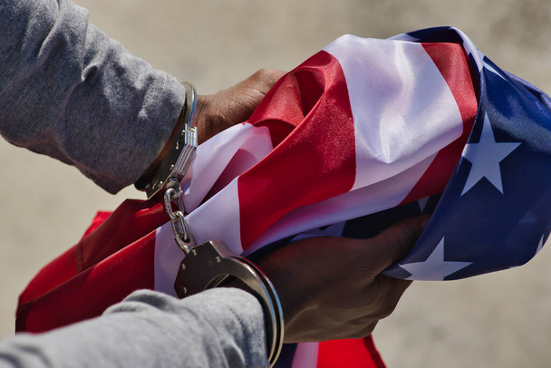 Detalhe de mãos afro-americanas em grilhões segurando uma bandeira dos Estados Unidos. Repressão racial. - Foto, Imagem