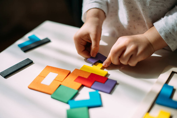 Child connects pieces of colored wooden puzzle. - Foto, immagini