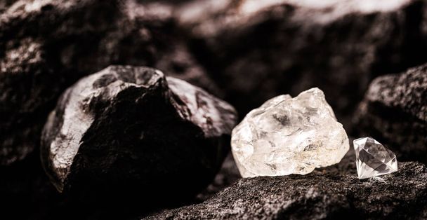 ruwe diamant naast een geslepen diamant, in een kolenmijn, concept van mijnbouw en minerale winning - Foto, afbeelding