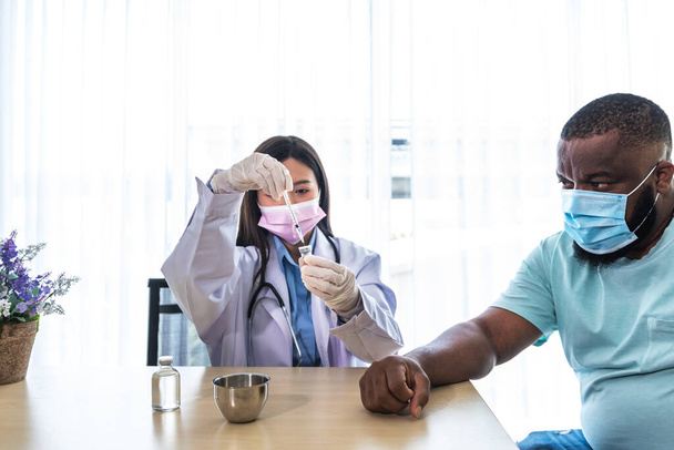 Asijská lékařka v chirurgické masce, která se dívá na vakcínu Covid-19 v rukou, se připravuje na očkování proti viru, proti arikánskému Američanovi, na koncepci zdravotní péče a očkovací látky. - Fotografie, Obrázek