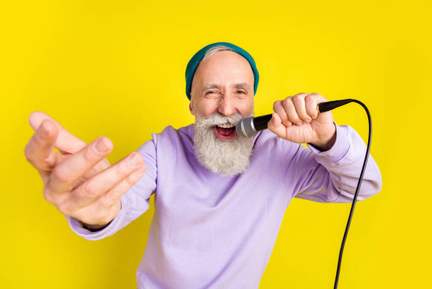 Photo of funny positive age gentleman wear violet sweater headwear dancing singing isolated yellow color background - Foto, Imagem