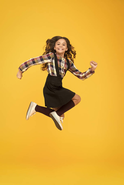 Time for fun. Active girl feel freedom. Fun and jump. Happy childrens day. Jump concept. Break into. Feel inner energy. Girl with long hair jumping on yellow background. Carefree kid summer holiday - 写真・画像