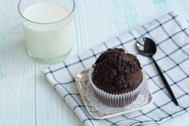 cupcake con gocce di cioccolato sta su un tovagliolo su uno sfondo leggero. - Foto, immagini
