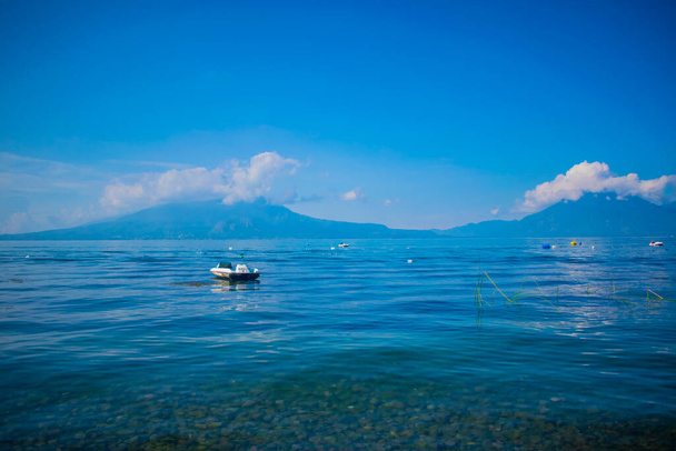 boat on the lake polluting with volcanoes from afar - Φωτογραφία, εικόνα