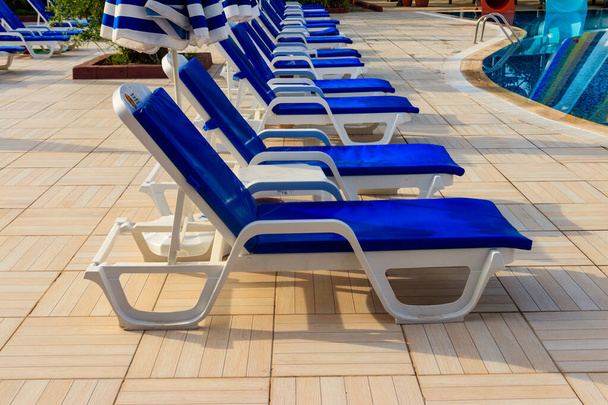 Chaise longues vicino a una piscina. Concetto di spa, riposo, relax, vacanze, resort - Foto, immagini