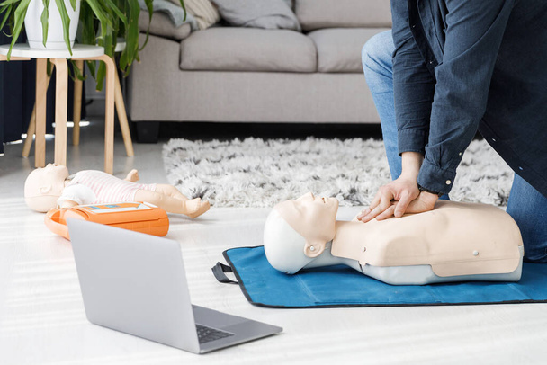 Paramedic demonstrating first aid on manikin during training alone in living room. The instructor showing CPR on training doll - Foto, afbeelding