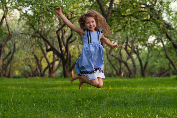 little girl runs barefoot on the grass. happy child on a hot summer day. - Zdjęcie, obraz