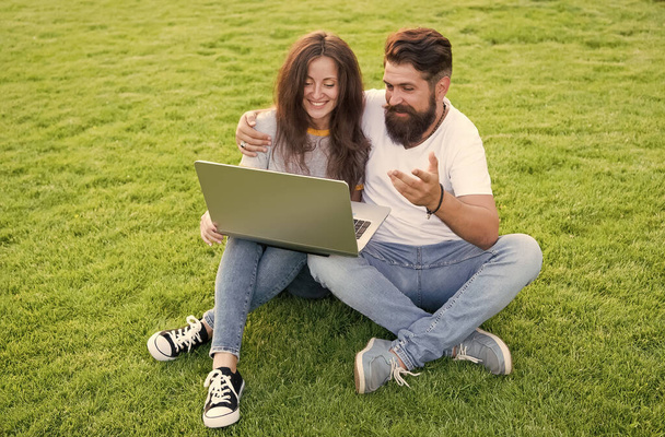 Modern entertainment. Bearded man and sexy woman use laptop. Couple in love rest on green grass. Enjoying modern computer technology. Modern life. Social media. Modern leisure. Summer vacation - Foto, Bild