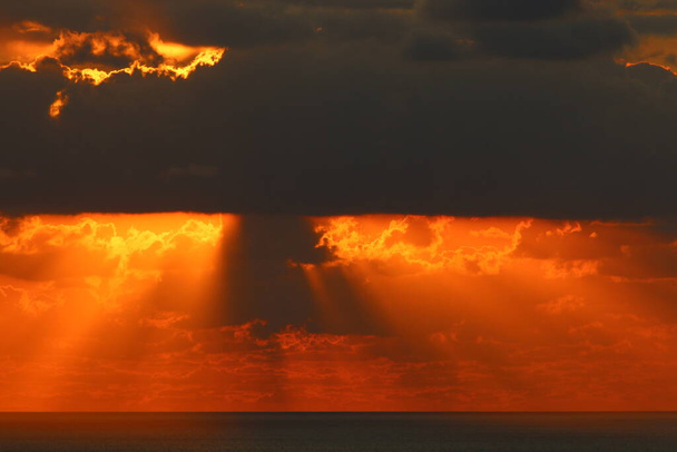 太陽は地平線の上に沈み空の燃えるような赤の照明に対して.  - 写真・画像