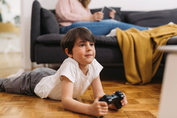 boy laying on floor playing video games at home - Foto, Imagen