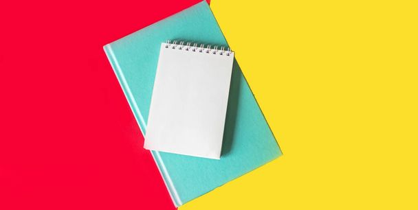 On a red and yellow background is a green diary and a notebook for writing down something - Foto, Imagem