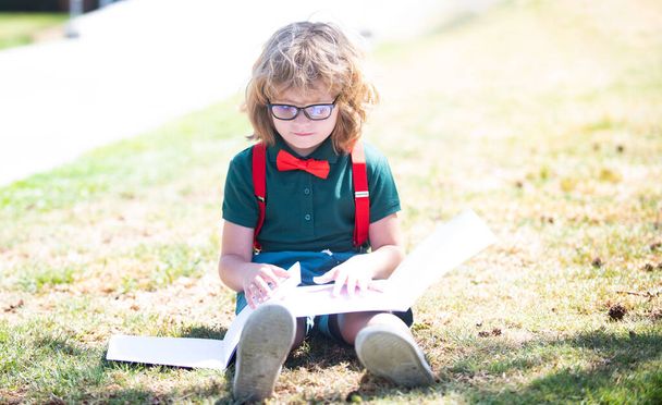 smart curious nerd in glasses reading book study with copybook outdoor, back to school - Photo, Image
