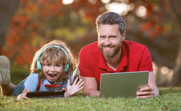 Отец и сын используют современные коммуникационные технологии в парке. семейный блог - Фото, изображение