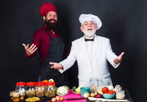 Kitchen battle. Two bearded professional chefs in uniform. Cooking time. - Photo, Image