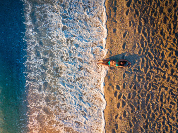 Gyönyörű fiatal nő napozik a víz szélén egy homokos strandon - Fotó, kép