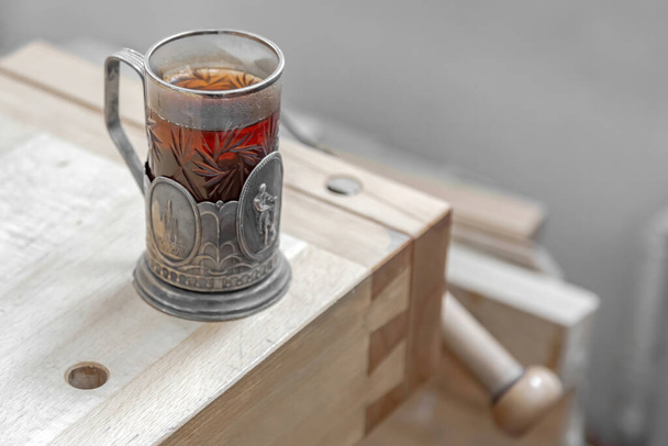Склянка гарячого чаю в старій срібній чашці на дерев'яному столі
 - Фото, зображення