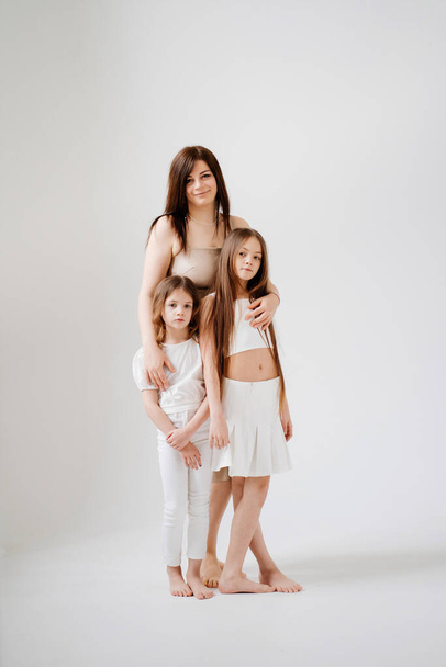Mom and daughters pose in a white photo studio. - Foto, imagen