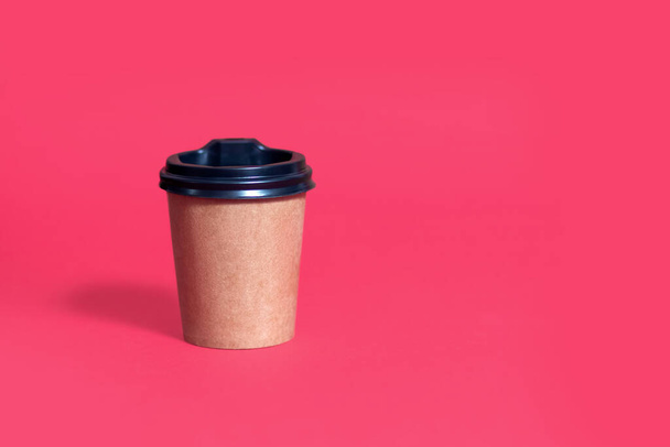 Χάρτινο φλιτζάνι καφέ με καπάκι σε κόκκινο φόντο με χώρο για κείμενο. Η έννοια της οικολογικής συσκευασίας σε μια σύγχρονη καφετέρια. Ποτήρι καφέ μιας χρήσης - Φωτογραφία, εικόνα