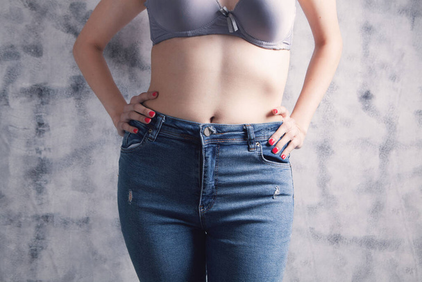 young woman posing in jeans and bras on gray background - Photo, image