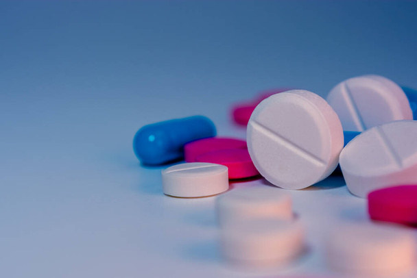Several scattered pills on the table close-up on a colorful background. Medical theme. Selective focus.  - Foto, Imagen