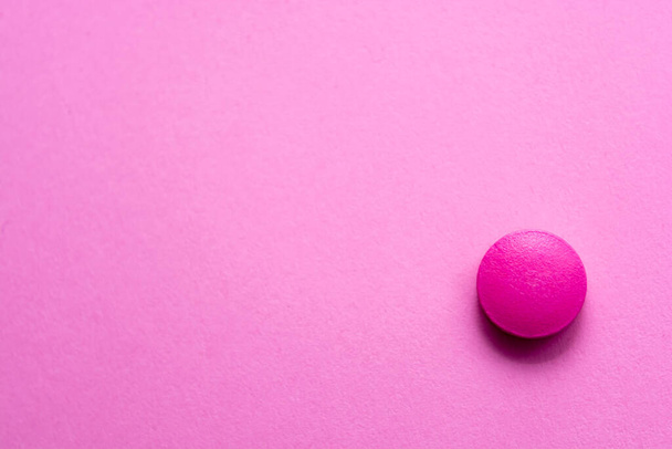 Pink pill on a pink table background close-up. Medical theme. Selective focus. - Fotó, kép