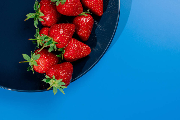 Ramo de fresa en plato sobre fondo azul. Verano baya roja estacional - Foto, Imagen