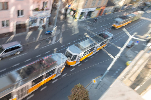 Shot from above, panning image keeps front car of one tram in focus while the rest of image is blurry showing movement.  Sofia, Bulgaria. - Fotoğraf, Görsel