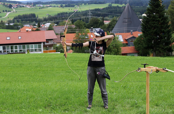Bowsport. Uma jovem mulher atirando arco e flecha em um campo - Foto, Imagem