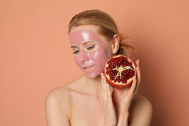 Young woman with pomegranate face mask and fresh fruit on pale coral background - Foto, imagen