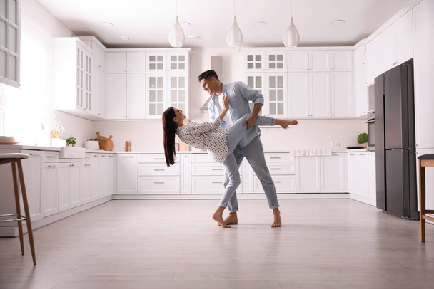 Happy couple dancing barefoot in kitchen. Floor heating system - Photo, image