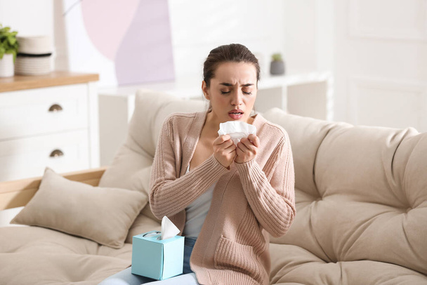 Young woman suffering from runny nose in living room - Φωτογραφία, εικόνα