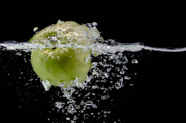 Fresh apple falls in water with air bubbles, black background, copy space - Фото, зображення