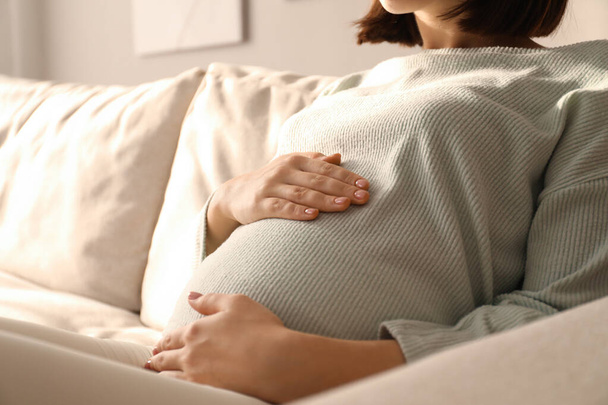 Pregnant young woman touching belly at home, closeup - Valokuva, kuva