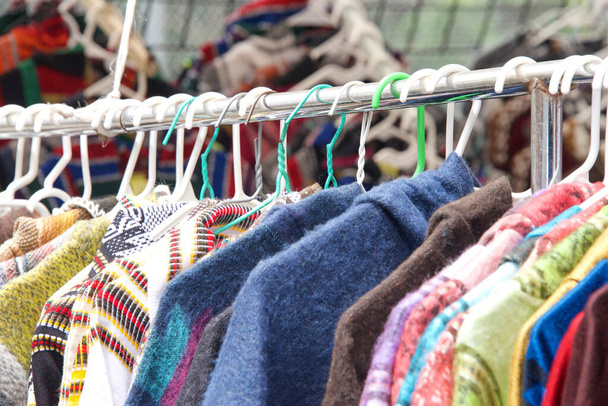 Nahaufnahme von Kleidungsstücken, die an einem Regal im Wiederverkaufsladen auf einem Straßenmarkt hängen. Gebrauchtkleidung. - Foto, Bild