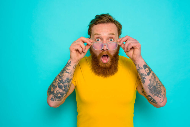 Man with yellow t-shirt and beard is shocked about something - Fotografie, Obrázek