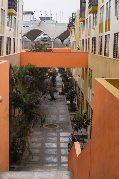 Fachada envejecida de moderno edificio residencial de varios pisos en el centro histórico de Lima Perú, paredes amarillas y naranjas, árboles. - Foto, Imagen
