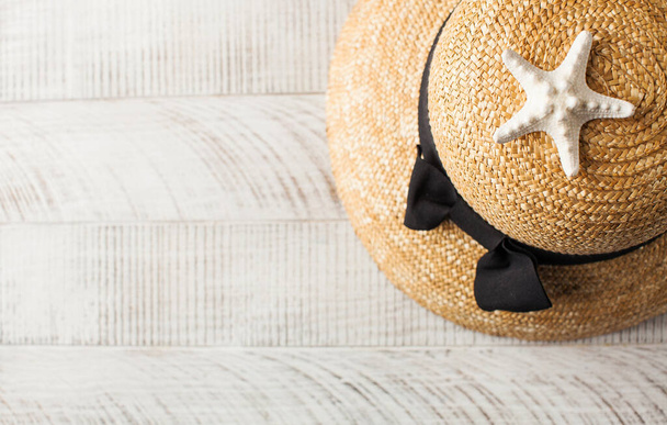 A straw hat and a starfish on a light wooden background. Summer background. Copy space. - Photo, image