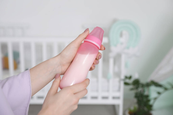 Bebek için bir şişe sütü olan kadın, yakın plan. - Fotoğraf, Görsel