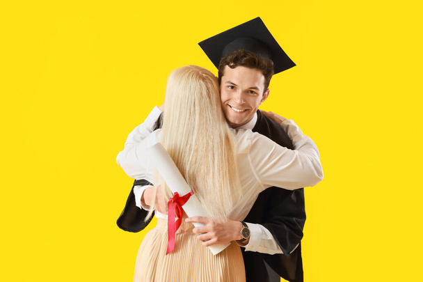 Happy male graduation student with his mother on color background - Photo, Image