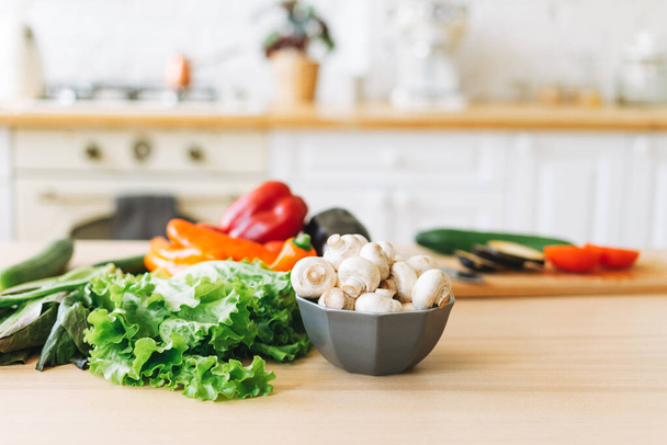 Свіжі овочі зелений салат, перець, гриби та баклажани на кухонному столі, процес приготування
 - Фото, зображення