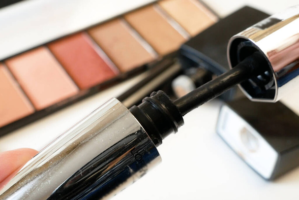 Mascara en set van cosmetische make-up producten achtergrond. Lippenstift, oogschaduw, penseel, poeder, lipgloss, close-up - Foto, afbeelding