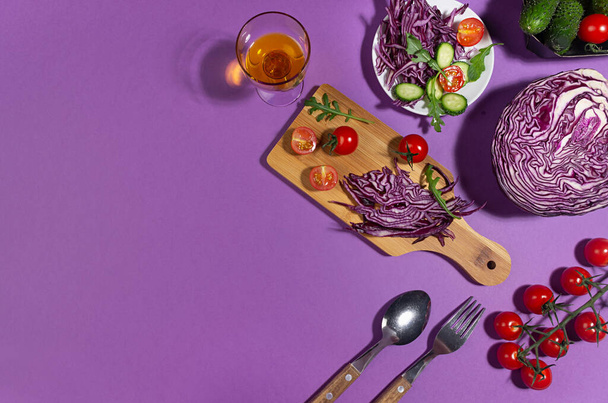 Recipe of fresh salad for fitness, dieting of raw vegetable with purple cabbage in sun light with shadow on bright violet color background, top view. - Fotó, kép